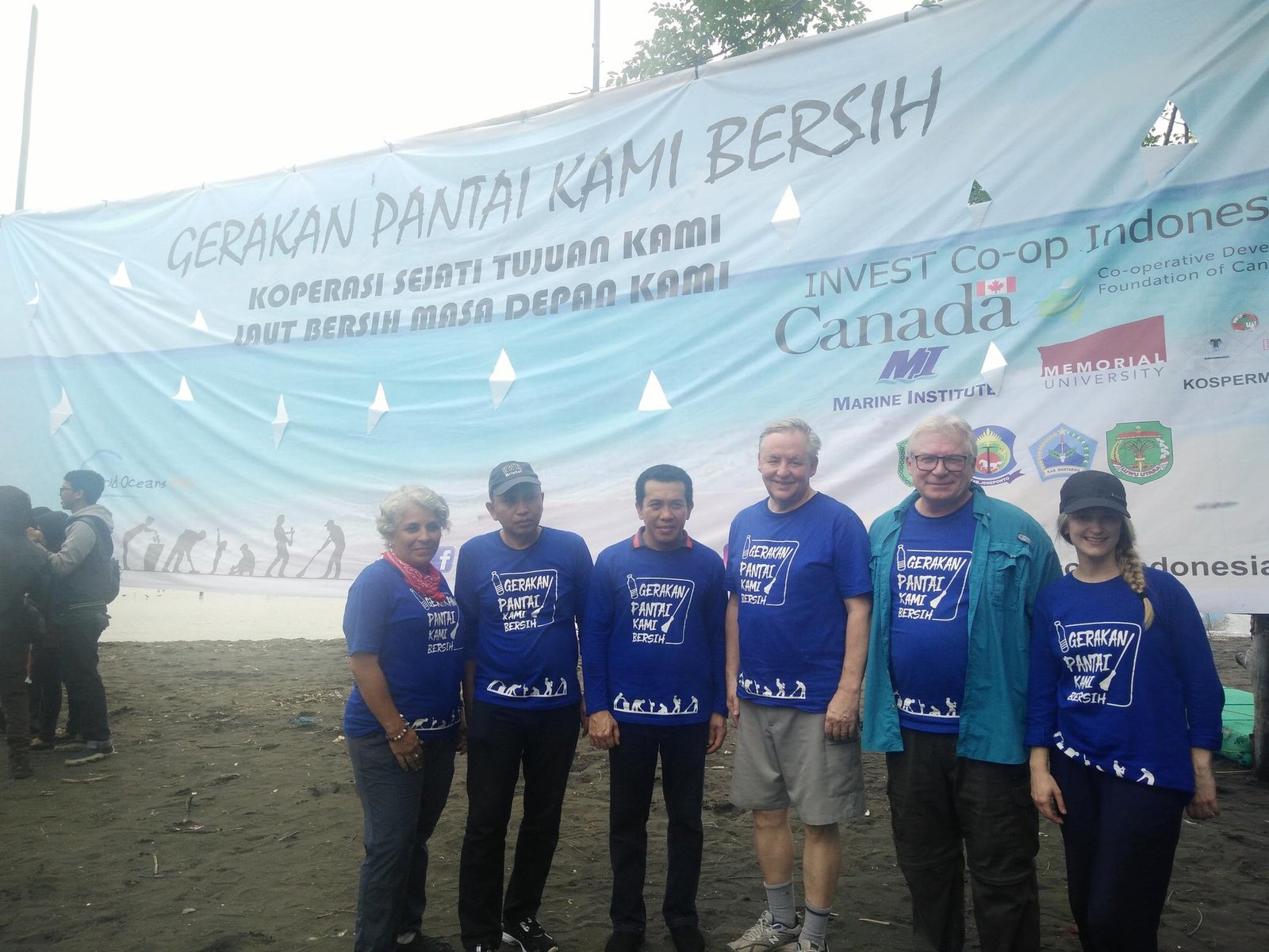 Kospermindo members and Canadian partners in front of a beach clean-up banner