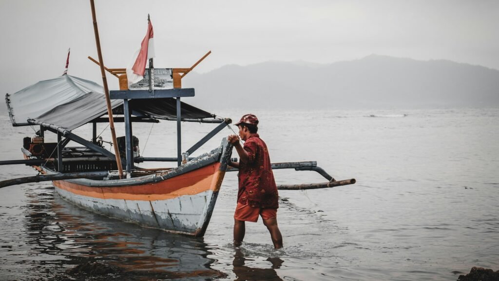 Man standing beside a boat on a beach